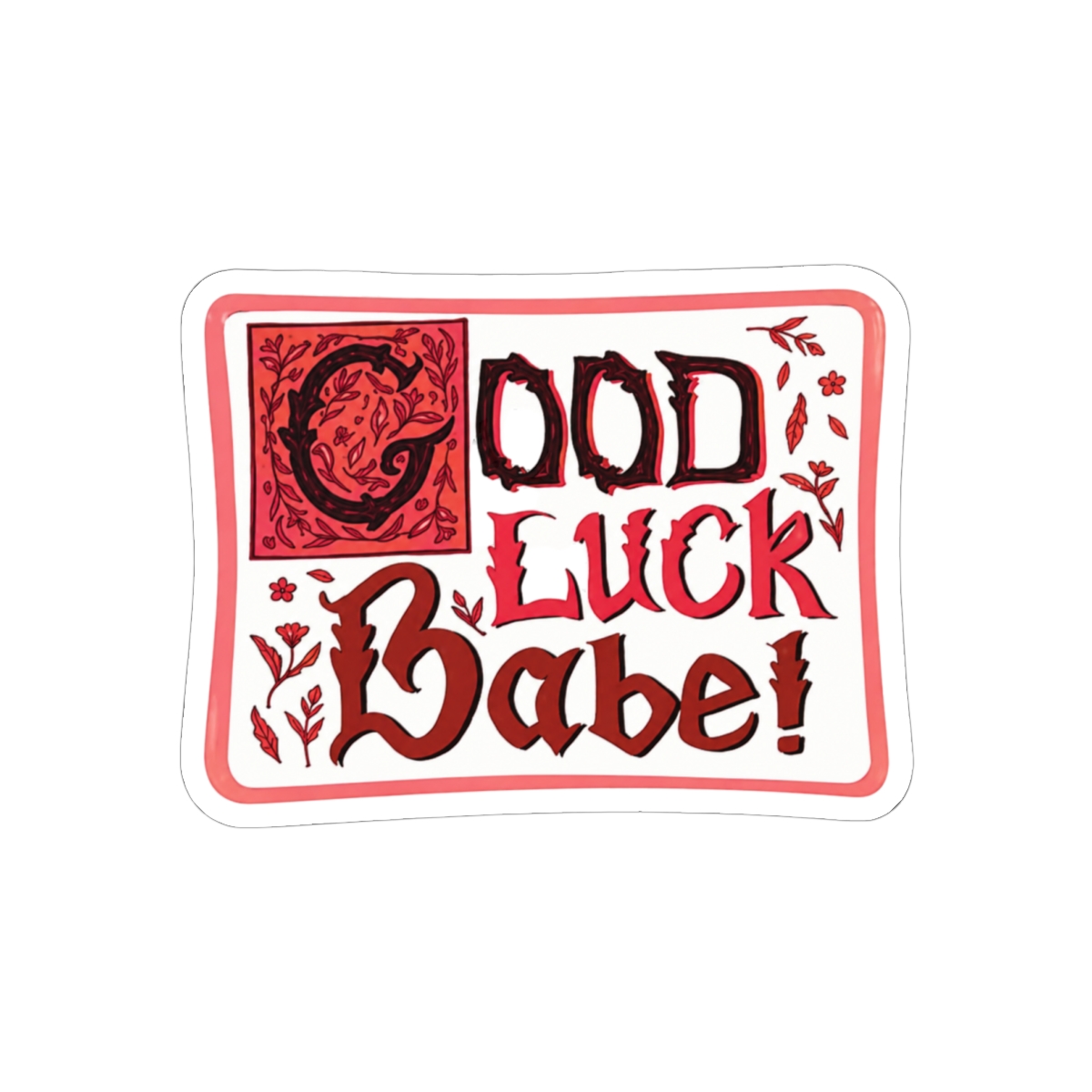 A pink sticker with the text "Good Luck Babe!" in a red and black font with floral accents
